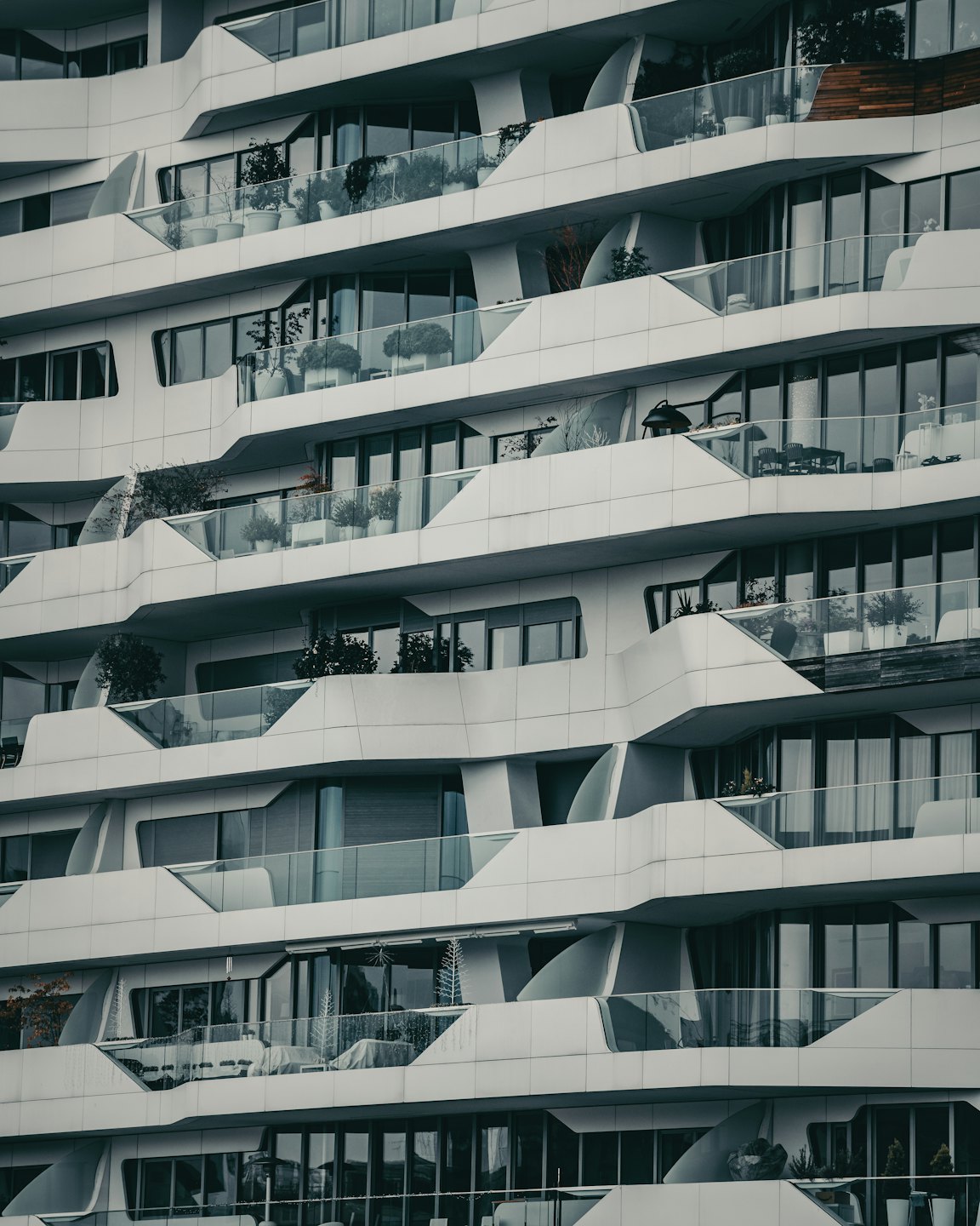 Beyaz kıvrımlı mimariye ve cam balkonlara sahip modern apartman binası.