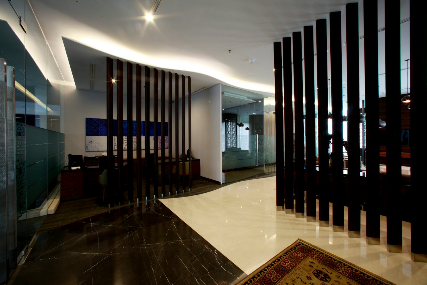 Mermer zeminli ve ahşap bölmeli modern ofis resepsiyon alanı.