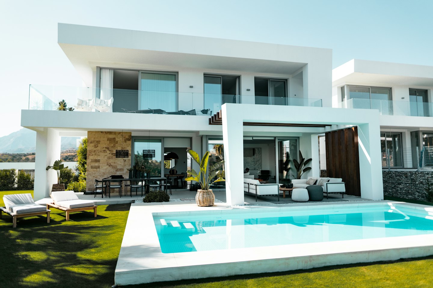 Güneşli bir günde havuzlu ve çimli modern beyaz villa.