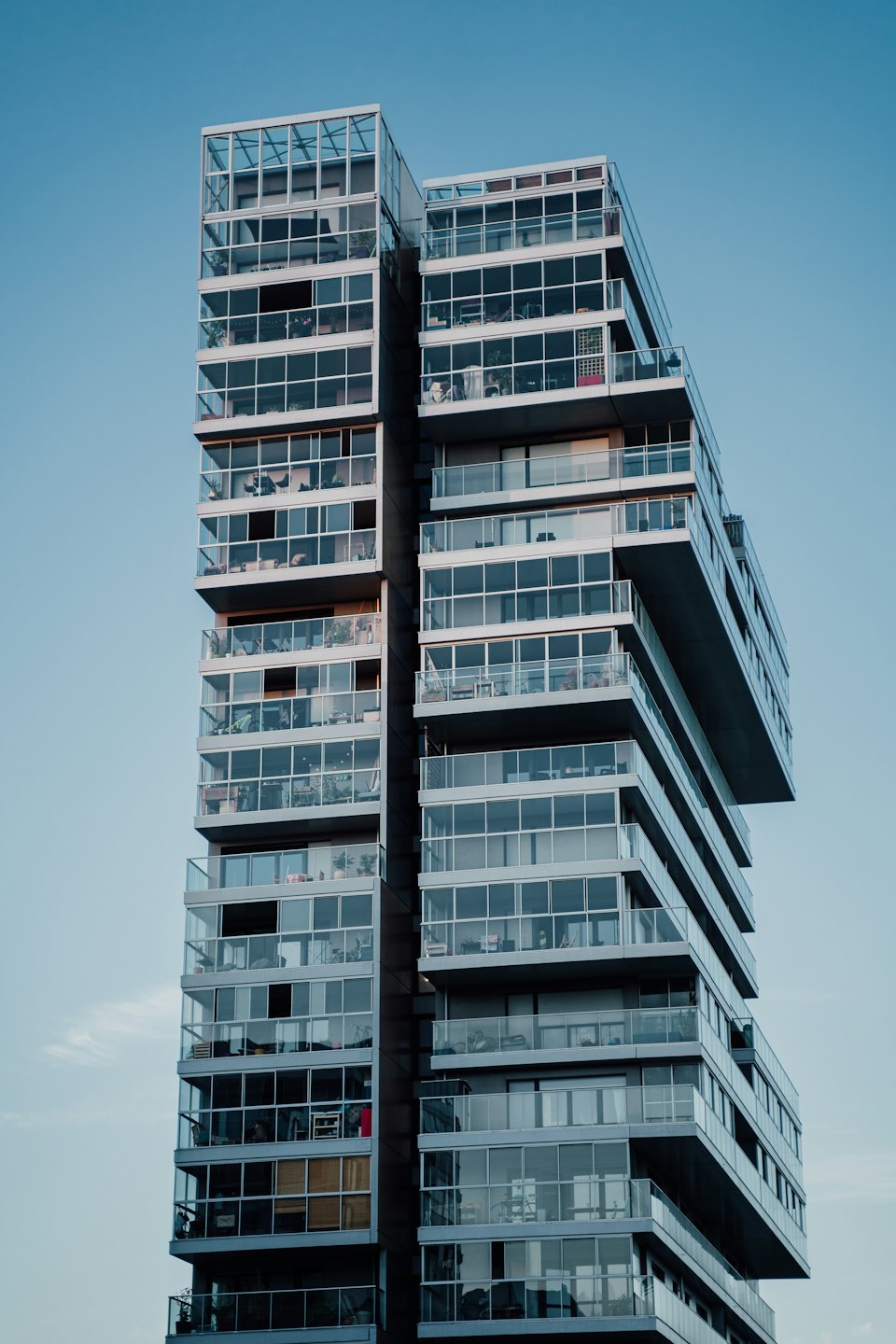 Modern apartman binası, balkonlu, açık gökyüzü altında.